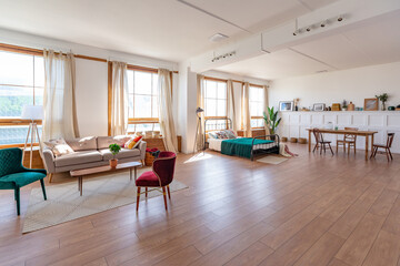 Vintage studio apartment interior in light colors in old style. huge room with large windows with a living room area and a bedroom area. direct sunlight inside.