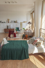 Vintage studio apartment interior in light colors in old style. huge room with large windows with a living room area and a bedroom area. direct sunlight inside.