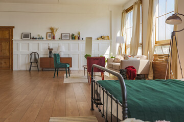 Vintage studio apartment interior in light colors in old style. huge room with large windows with a living room area and a bedroom area. direct sunlight inside.