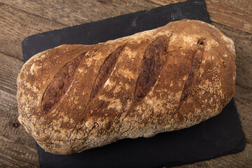 Freshly baked bread loaf on black slate 