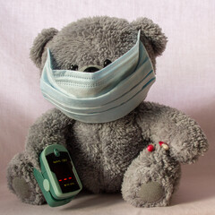 teddy bear in mask and pulse oximeter 