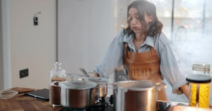 Tired and sad housewife standing hopelessly in a smoky kitchen from burnt food. Exhaustion from household chores and home routine concept