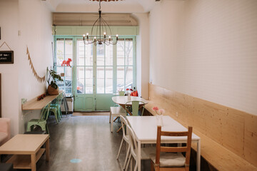 Cozy interior of confectionery cafe with simple furniture and vintage lamp in light room with old fashioned door