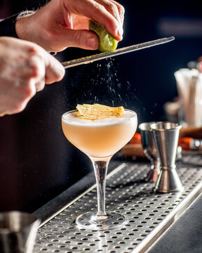 barman rubs lime zest on cocktail. bartender is preparing a cocktail for serving.Finishing a Cocktail. Mixology