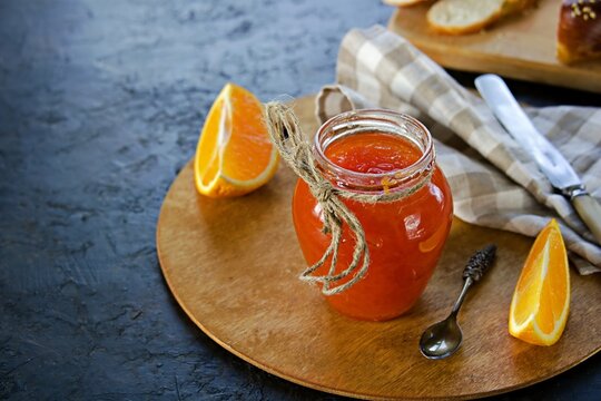 Carrot jam with orange in a glass jar on a black concrete background. Vegetable jams.