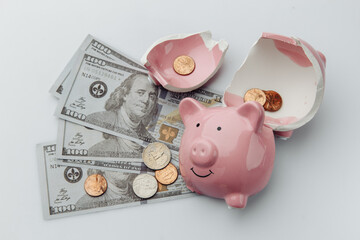 Broken piggy bank with dollar bills on a white background.