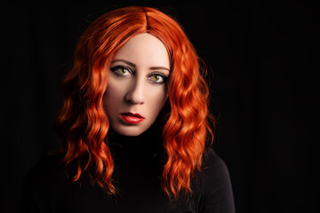 Beautiful girl with long wavy ginger hair on a black background