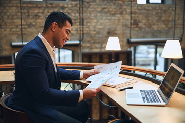 Smiling man studying documents at the desk