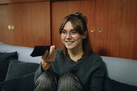 Girl sitting on a sofa and using a remote control television
