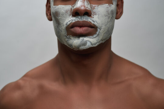 Face closeup of shirtless young african american man using facial blackhead removal mask, posing isolated over gray background