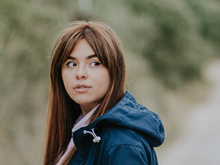 Chica pelirroja vestida con una chaqueta azul mirando algo en el campo