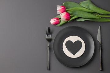 Festive creative black table setting with heart and tulip bouquet on dark background. Valentine's Day, Wedding Day, Birthday, Women's Day and Mother's Day. Flat lay. Copy space.