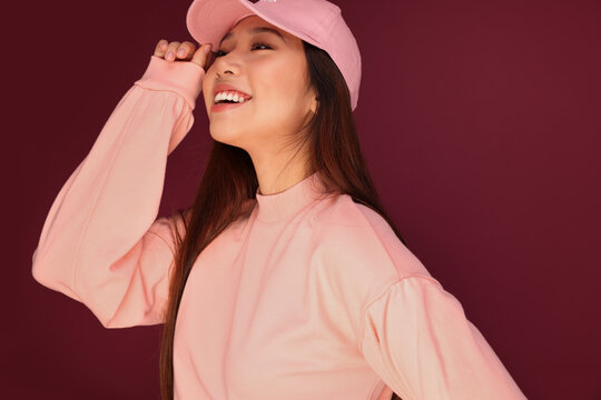 Portrait of happy young asian woman in the studio wearing pink clothes over garnet background