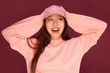 Portrait of happy young asian woman in the studio wearing pink clothes over garnet background