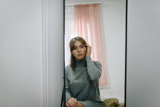 Blonde girl combing her hair in front of a mirror