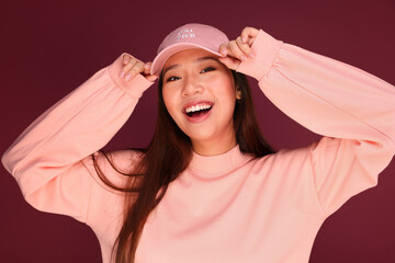 Portrait of happy young asian woman in the studio wearing pink clothes over garnet background