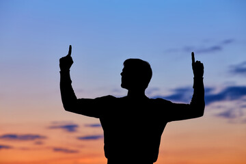 Men silhouette at sunset, human body over natural colorful sky background, hands up having fun