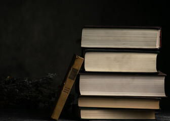 Viejos libros sucios apilados sobre una madera rústica y un fondo oscuro con poca luz