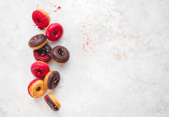 Flying Valentine's Day Donuts. Colorful mini  donuts with chocolate, icing and sugar sprinkles on rustic white background