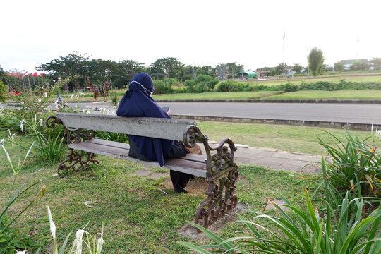 Sendawar Kutai Barat, Indonesia - January 10, 2021: Hijab woman relax sitting on the chair in beautiful park garden