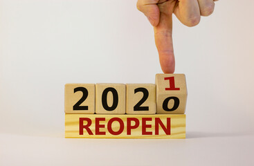 Business concept of new year 2021 reopen. Businessman flips a wooden cube and changes words 'reopen 2020' to 'reopen 2021'. Beautiful white background, copy space. Business, reopen 2021 symbol.