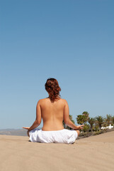 woman dressed in white performing meditation and yoga postures on the sand dunes on sunny day