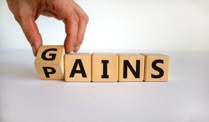 Gains and pains symbol. Businessman turns wooden cubes, changes word pains to gains. Beautiful...