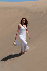 woman dressed in white enjoying in the sand dunes on the sunny day