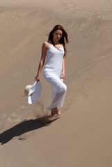 woman dressed in white enjoying in the sand dunes on the sunny day