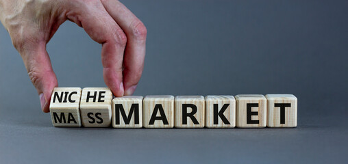 Mass or niche market symbol. Businessman flips wooden cubes and changes words 'mass market' to...