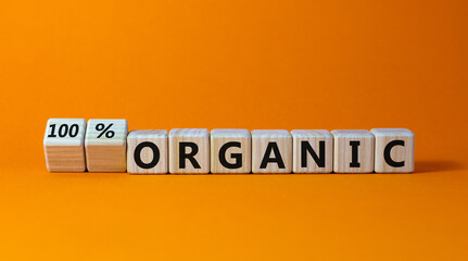 100 percent organic symbol. Fliped wooden cubes and changed words 'organic' to '100 percent organic'. Beautiful orange background, copy space. Business, healthy lifestyle organic concept.