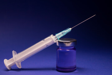 Vaccine bottle phial with no label, medical syringe injection needle. isolated on blue background....