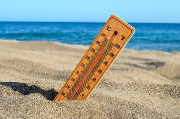 Thermometer on the Sand Beach, Hot climate concept with wooden Thermometer