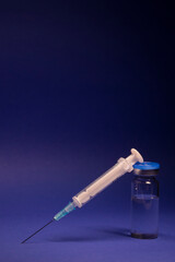 Vaccine bottle phial with no label, medical syringe injection needle. isolated on blue background. Development of coronavirus vaccine COVID-19. cure. World race in researching