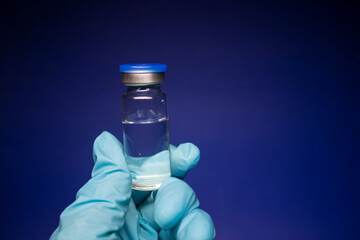 Development of coronavirus vaccine COVID-19. bottle phial with no label in blue medical glove....