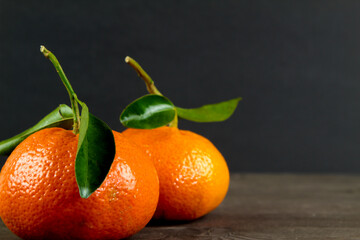 Two tangerines with green leaves on black background