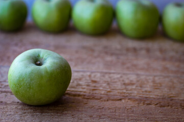 Green apples stand on a wooden surface