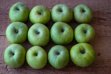 Green apples stand on a wooden surface