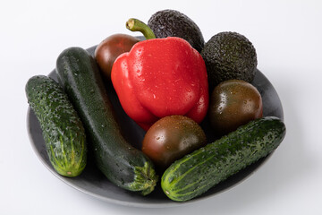 Fresh vegetables with water droplets from market, on grey plate with white background