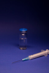 Vaccine bottle phial with no label, medical syringe injection needle. isolated on blue background. Development of coronavirus vaccine COVID-19. cure. World race in researching