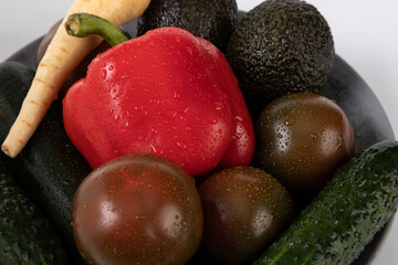 Fresh vegetables with water droplets from market, on grey plate with white background