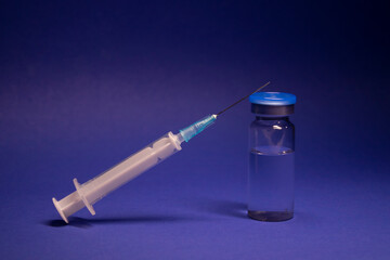 Vaccine bottle phial with no label, medical syringe injection needle. isolated on blue background....