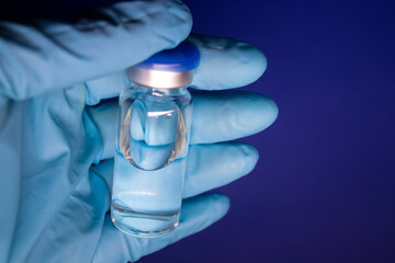 Development of coronavirus vaccine COVID-19. bottle phial with no label in blue medical glove....