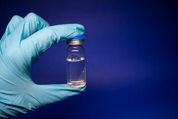 Development of coronavirus vaccine COVID-19. bottle phial with no label in blue medical glove....