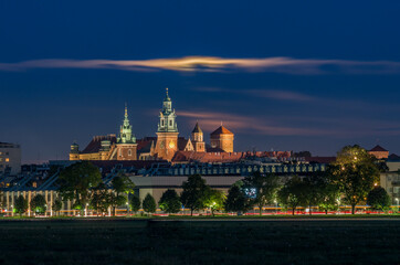 Wawel Castle and cloud illuminated by full moon, Krakow, Poland, seen from Blonia meadow.
