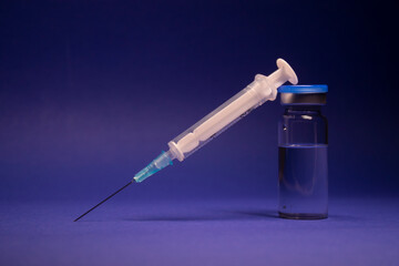 Vaccine bottle phial with no label, medical syringe injection needle. isolated on blue background....