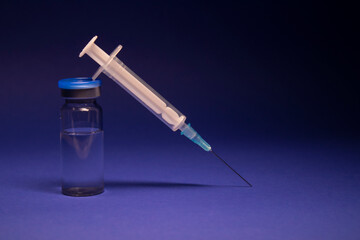 Vaccine bottle phial with no label, medical syringe injection needle. isolated on blue background....