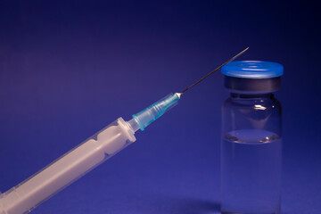 Vaccine bottle phial with no label, medical syringe injection needle. isolated on blue background....