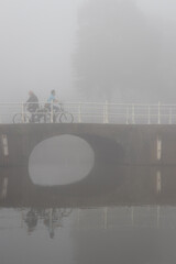 People cycling or waking outdoors during a very foggy, misty day