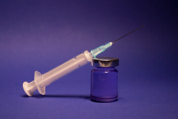 Vaccine bottle phial with no label, medical syringe injection needle. isolated on blue background....